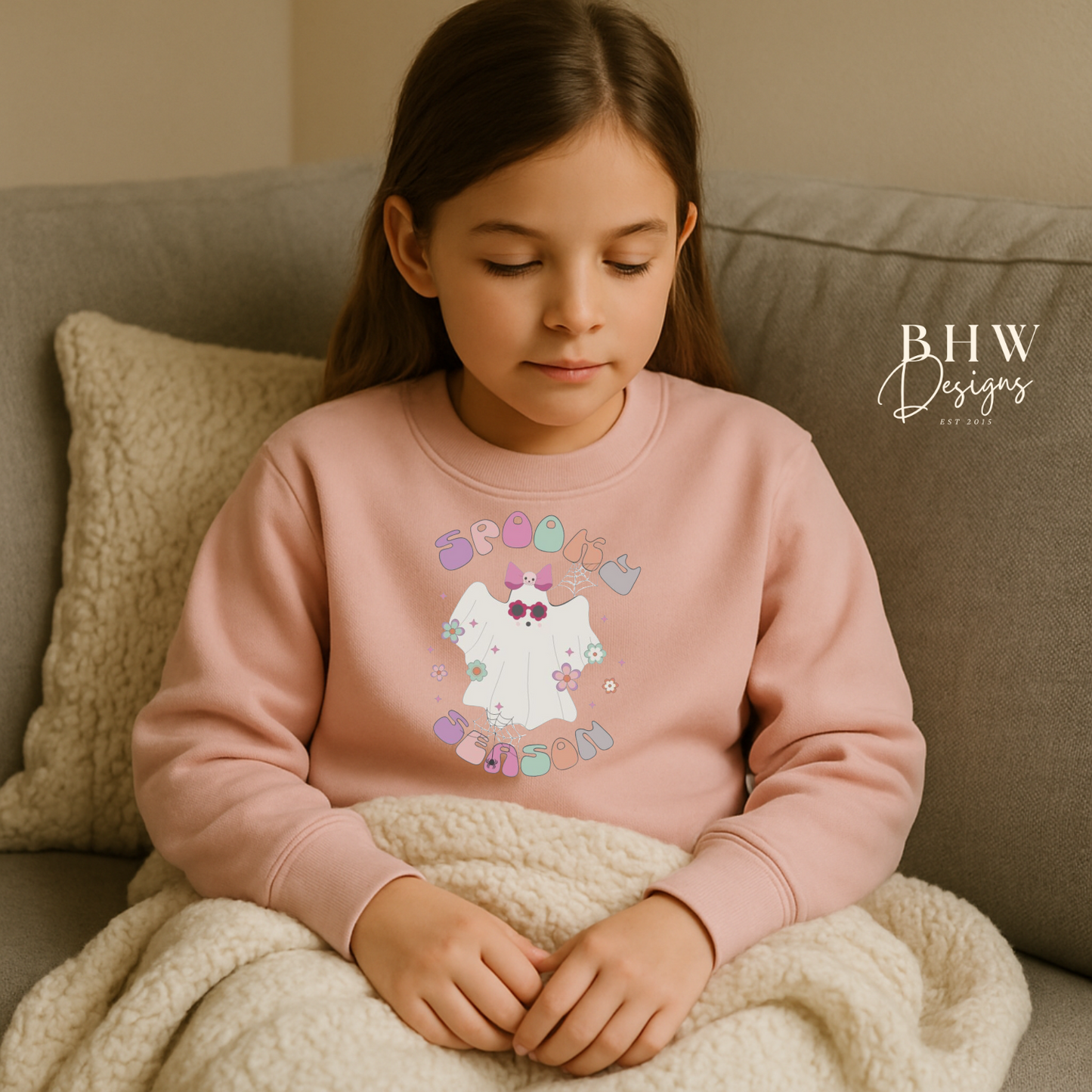 Young Girl wearing a pink sweatshirt with spooky season ghost design on the front