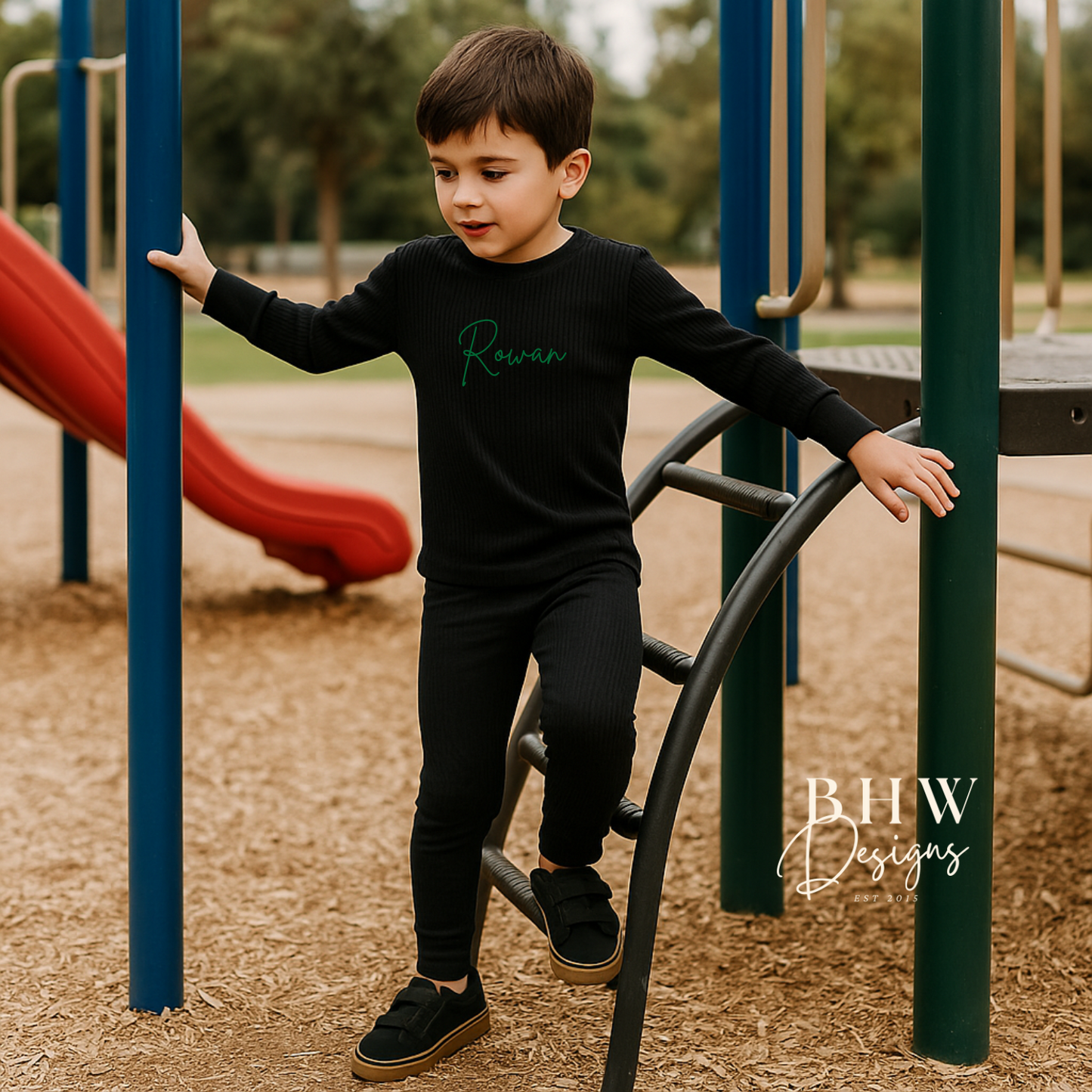 Boy wearing a black ribbed outfit with personalised Rowan on the front in Green.
