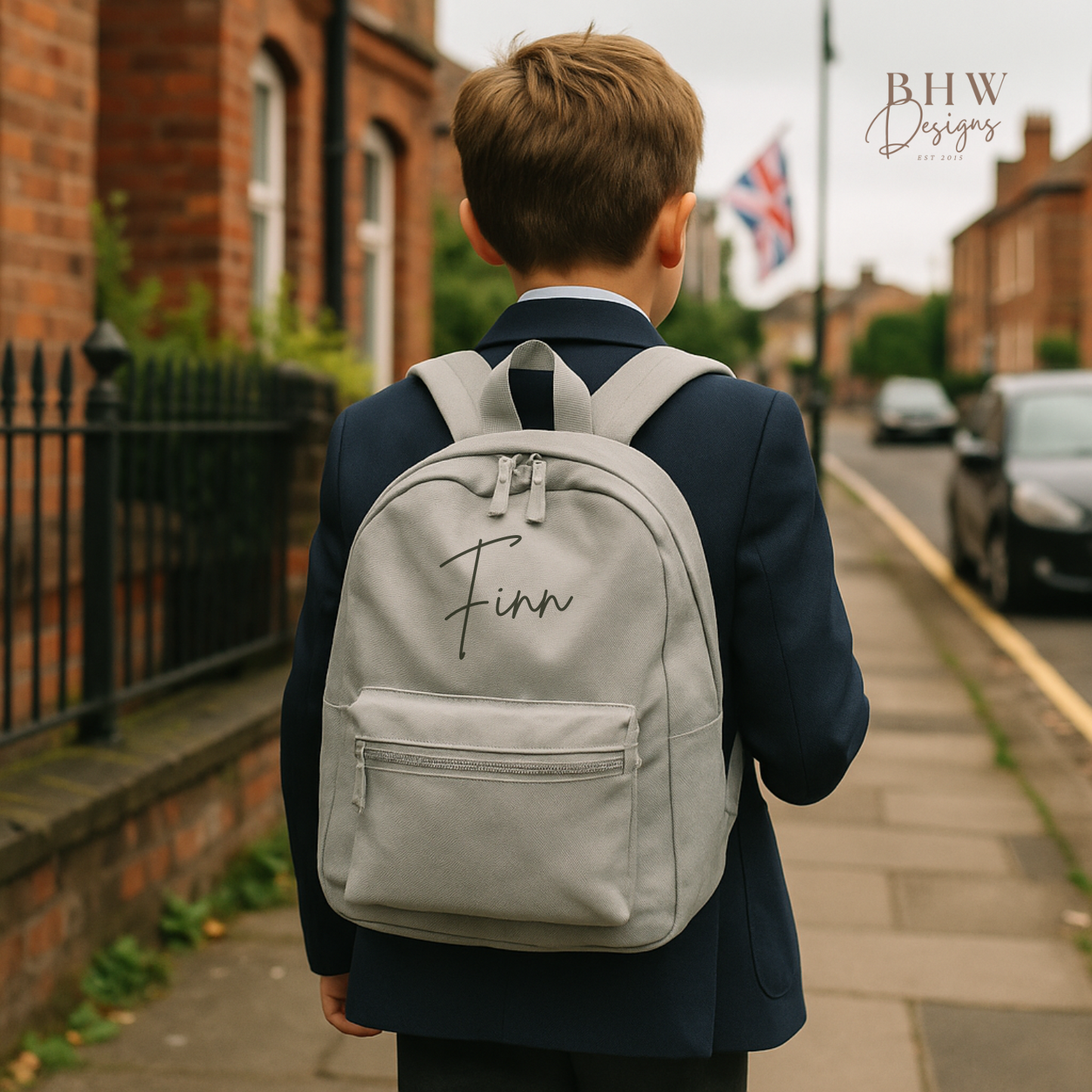 Person wearing a gray backpack with 'Finn' written on it, standing on a street.