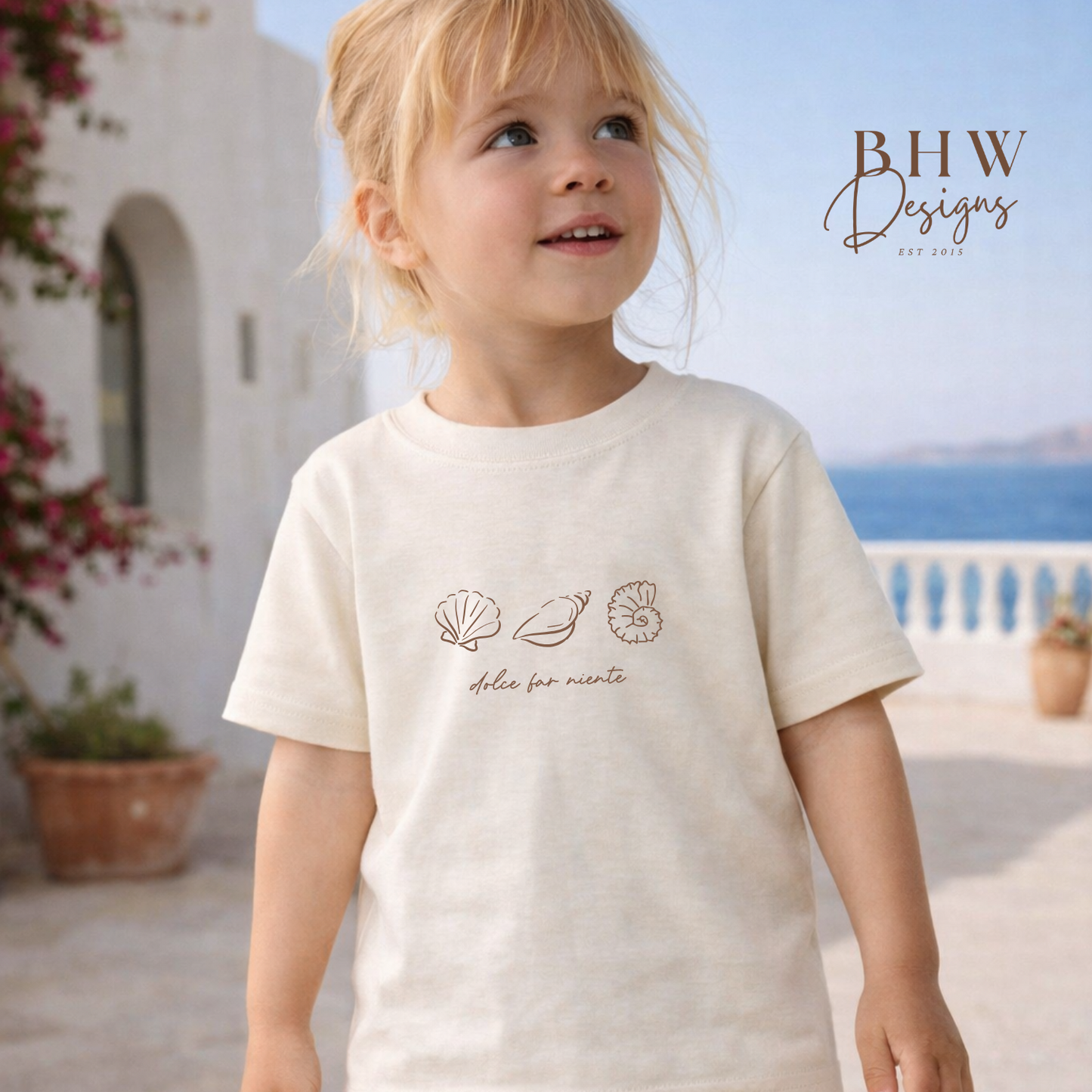 Child wearing a white t-shirt with shell designs outdoors