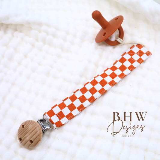 An orange and white checkered dummy clip with a wooden clip and chain attachment on a white background.