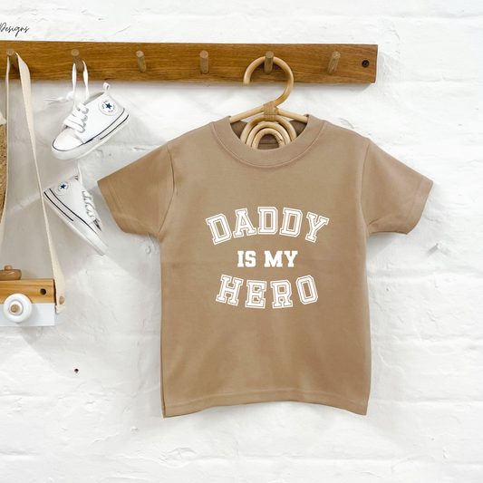 Children's beige t-shirt with 'Daddy is my hero' text on a white background