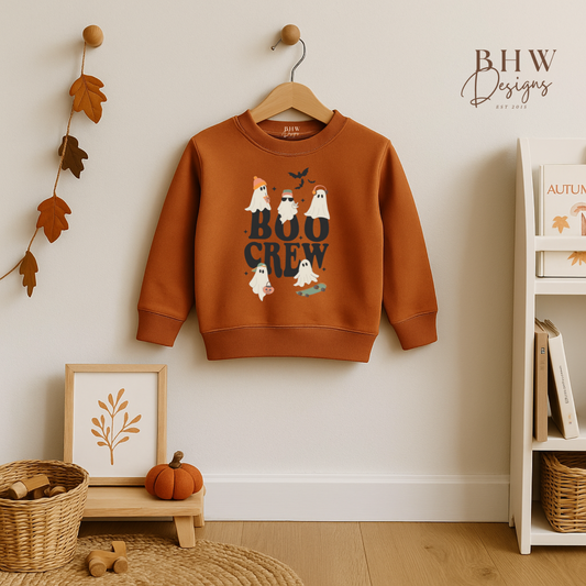 Children's rust orange sweatshirt with 'Boo Crew' design on a hanger against a white wall.