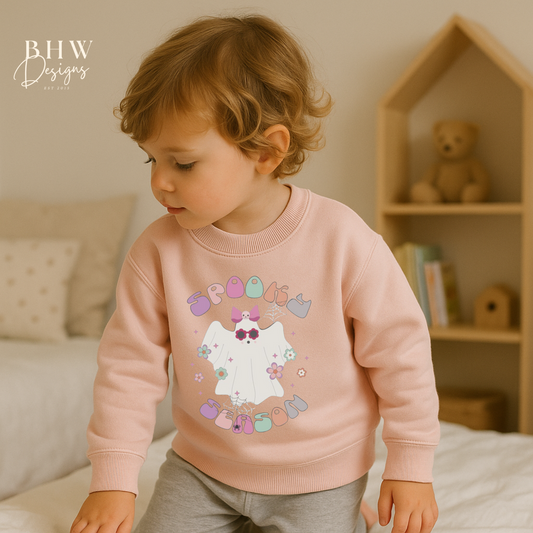 Child wearing a pink sweatshirt with spooky season ghost design on the front