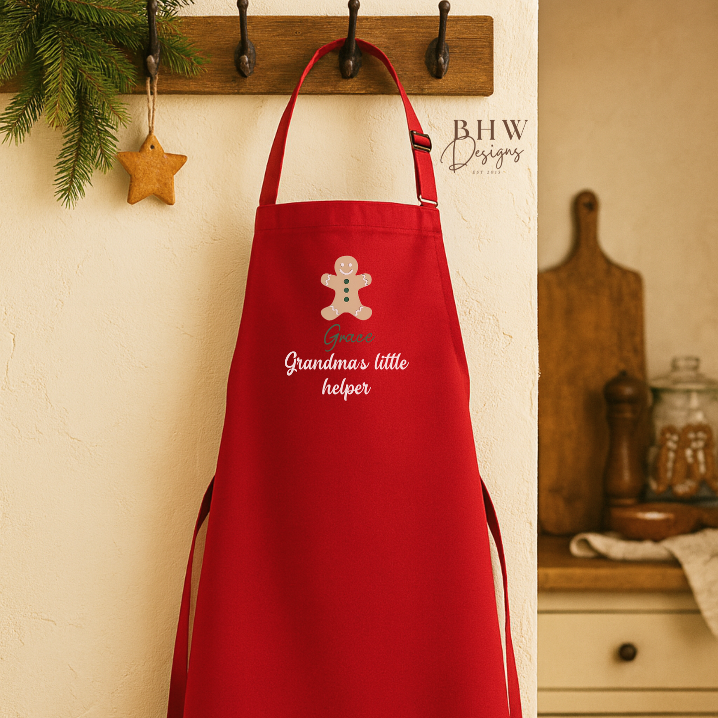 Red apron personalised and gingerbread man design hanging on a wall with kitchen background.