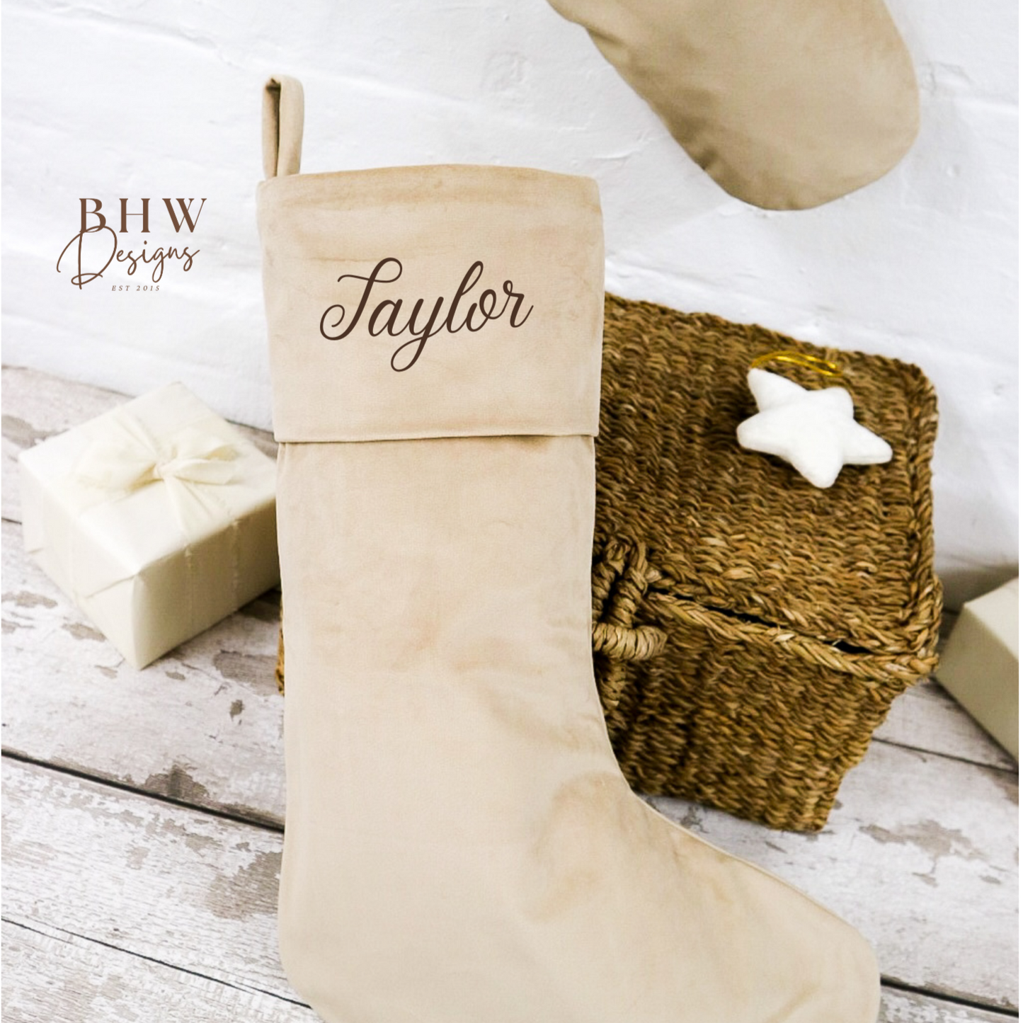 Beige Christmas stocking with 'Taylor' personalised on it, placed on a wooden surface.
