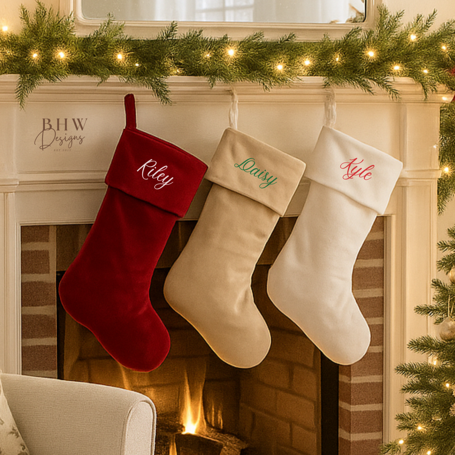 Three personalised Christmas stockings hanging by a fireplace with a candle on a table in front.