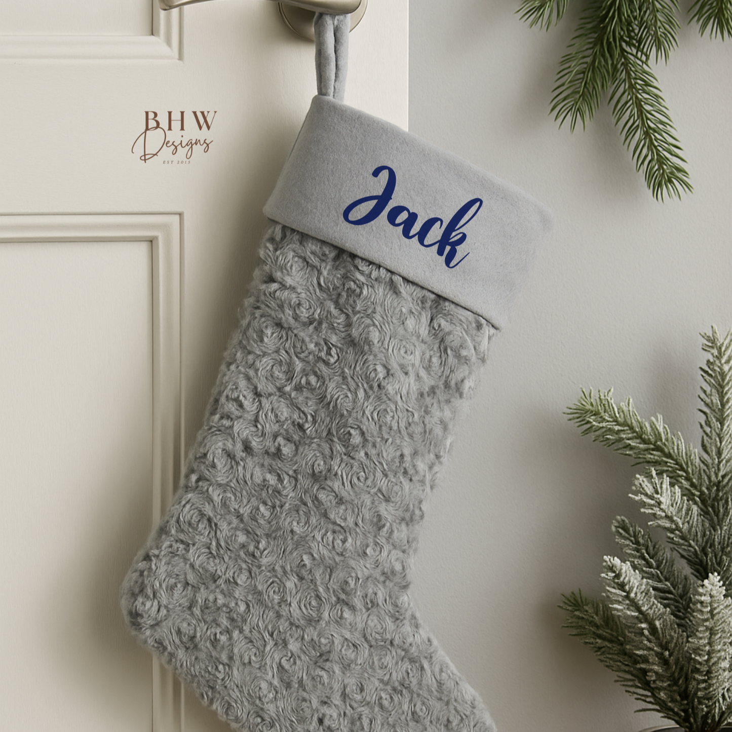 Grey textured Christmas stocking with 'Jack' on it, hanging on a door handle.