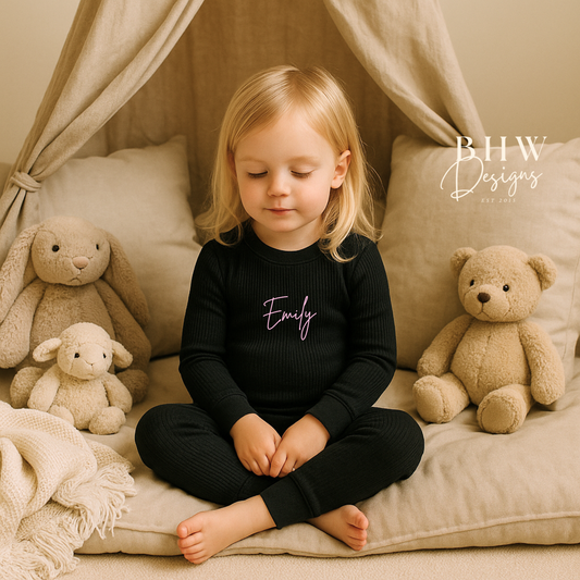 Girl wearing a black outfit with 'Emily' printed on it in baby pink