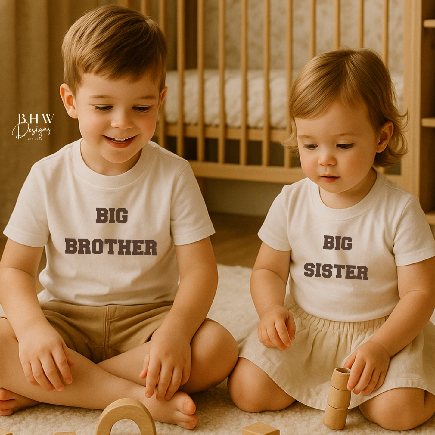 Two children wearing 'Big Brother' and 'Big Sister' shirts, sitting on the floor with wooden toys.