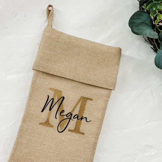 Burlap stocking with 'Megan' printed on it, hanging against a white background.