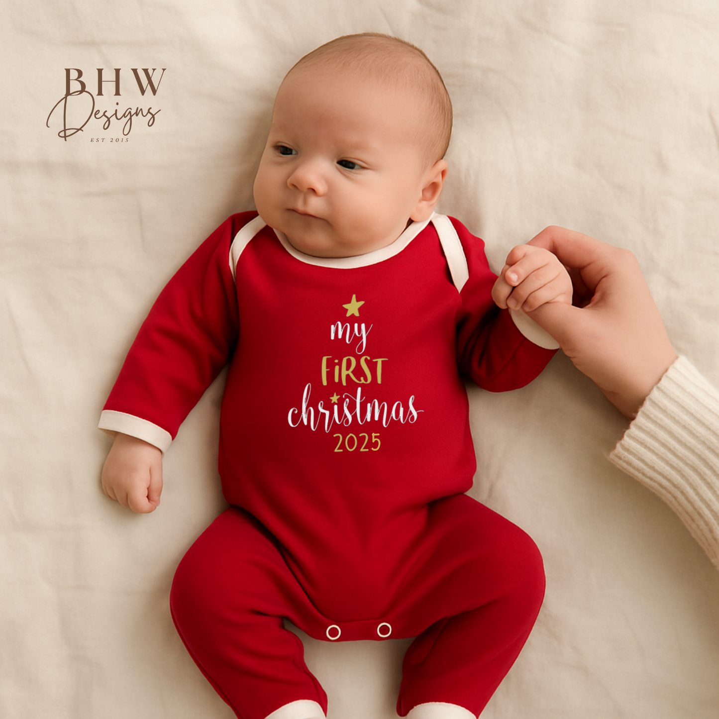 Baby wearing a red 'My First Christmas 2025' onesie on a white blanket