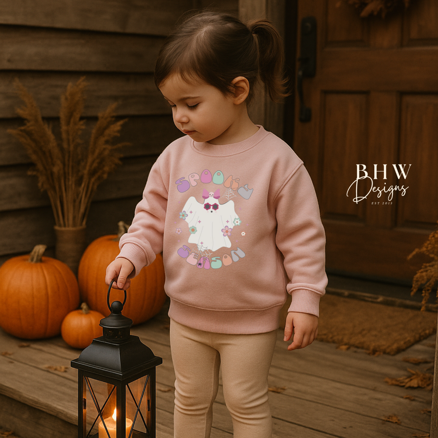 Child wearing a pink sweatshirt with spooky season ghost design on the front 