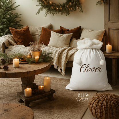 Cozy living room with a a white Santa sack with white faux fur trim and pom pom's with Clover on the front in brown 