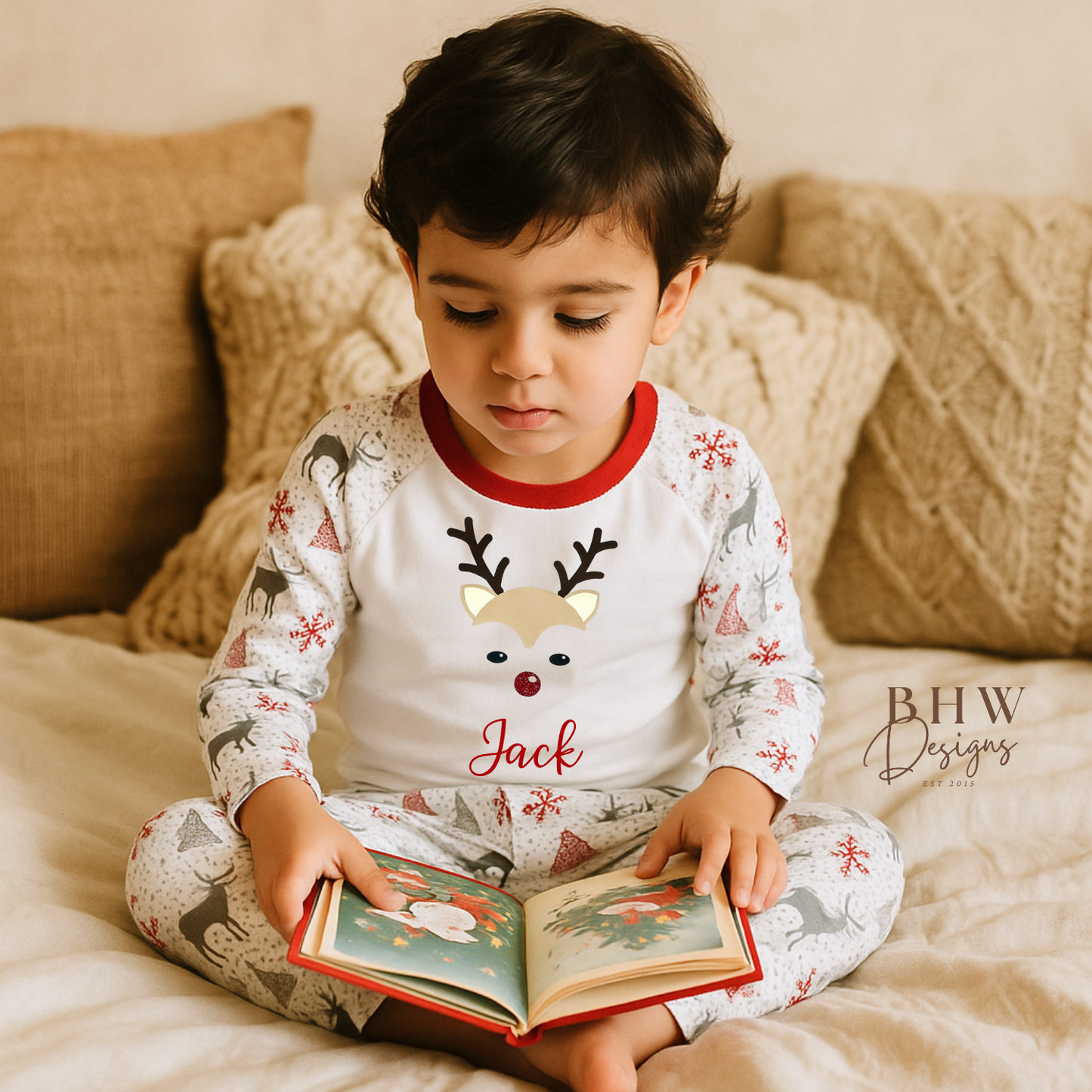 Child in festive personalised pyjamas reading a book on a cozy couch
