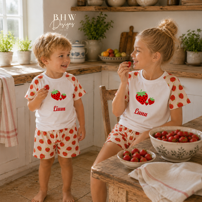 Two children in matching strawberry-themed outfits in a kitchen setting.