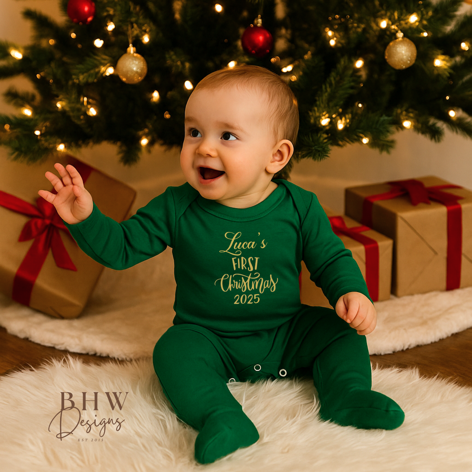 Baby in a green onesie  with Luca's First Christmas 2025 On the front in Gold