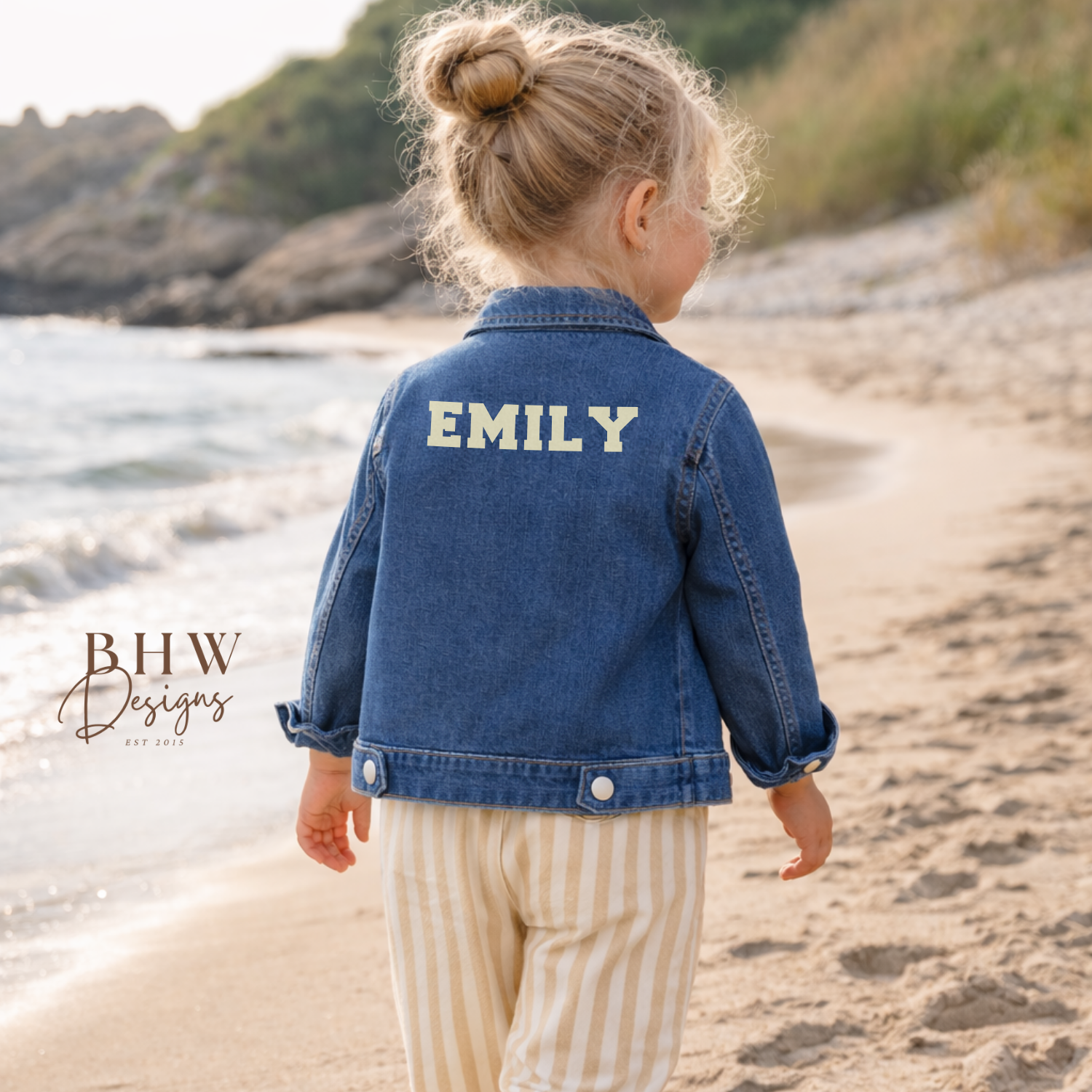 Child wearing a denim jacket with 'EMILY' on the back in cream