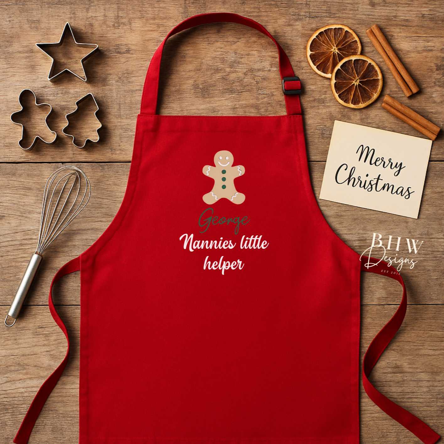 Red apron with a gingerbread design and text on a wooden surface with baking tools.