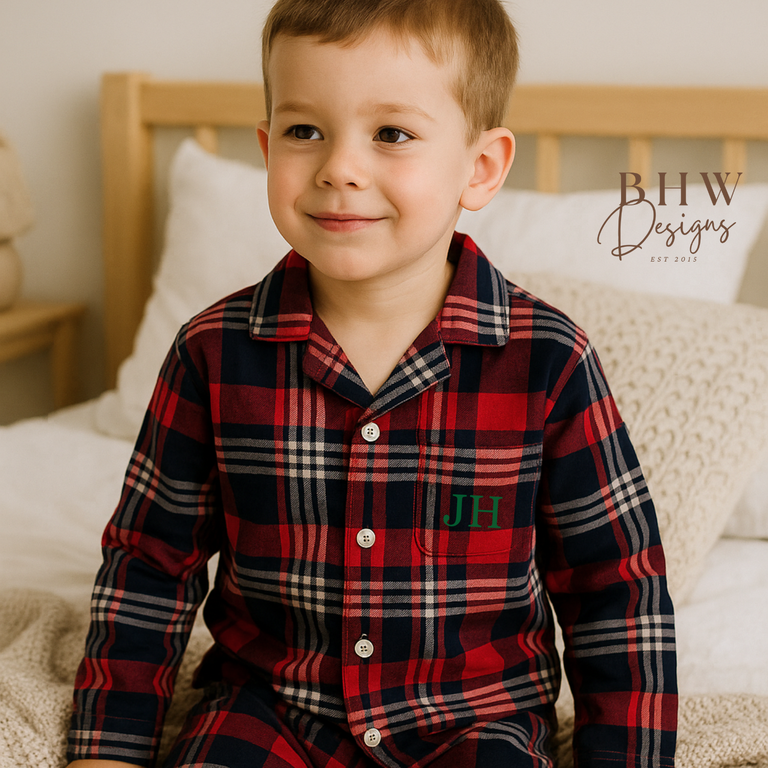 Child wearing a red and blue plaid pyjama set with 'JH' initials. 