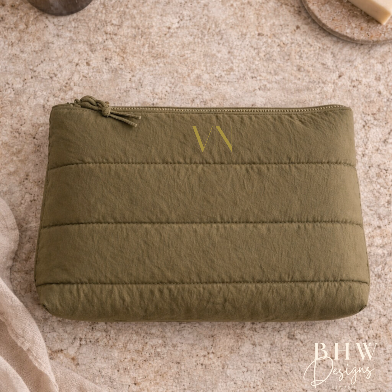 Green pouch on a textured surface with a bottle and soap bar in the background