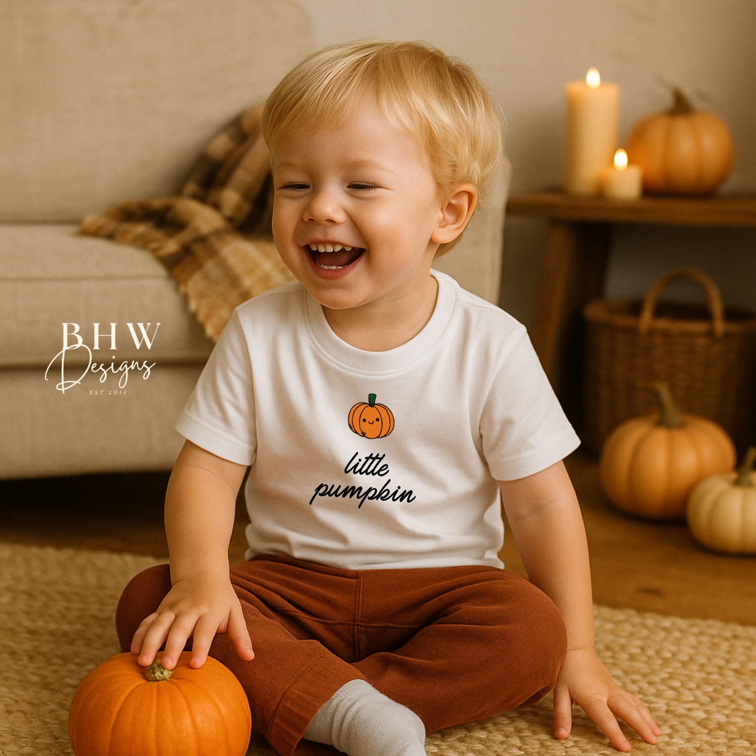 Child wearing a 'little pumpkin' shirt with pumpkins in the background