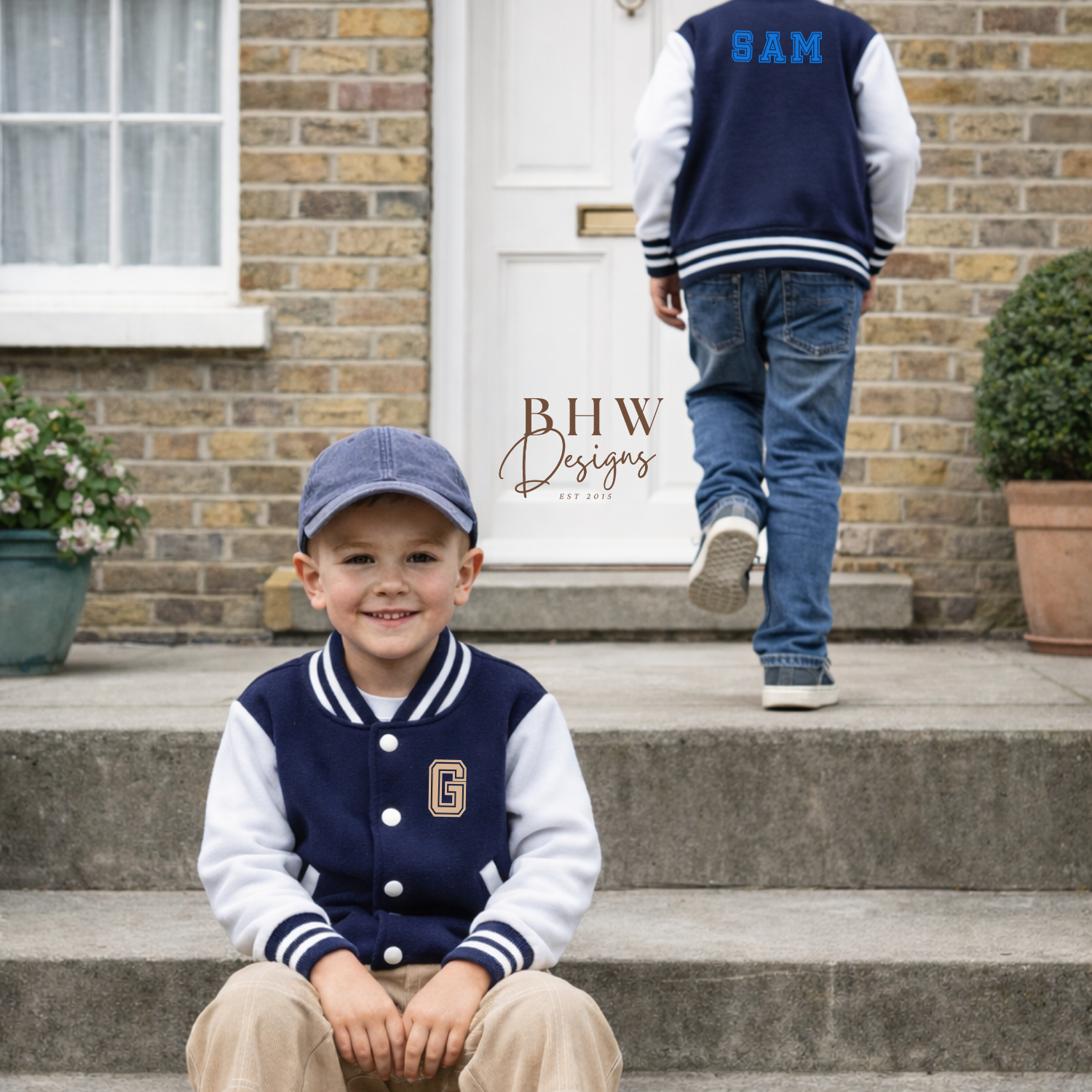 Two children wearing navy and white varsity jackets with letterman design in front of a house.