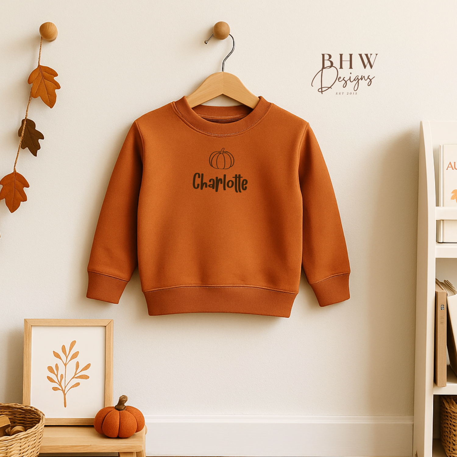 Rust Orange sweatshirt with 'Charlotte' printed on it hanging on a wooden hanger against a white wall.