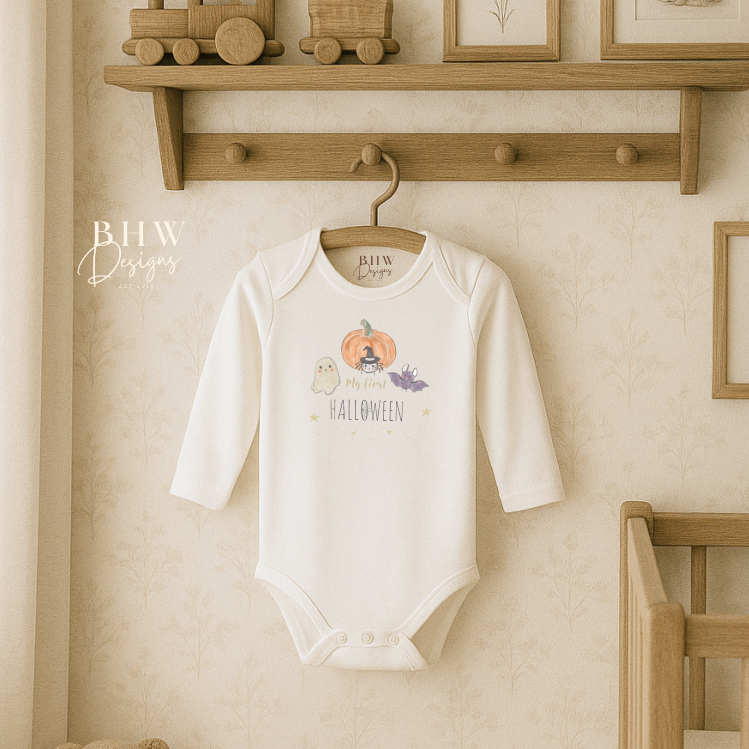 Baby onesie with my first Halloween design hanging on a wooden hook against a neutral wall.