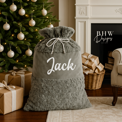 Grey Christmas sack with 'Jack' written on it, placed in front of a decorated Christmas tree and fireplace.