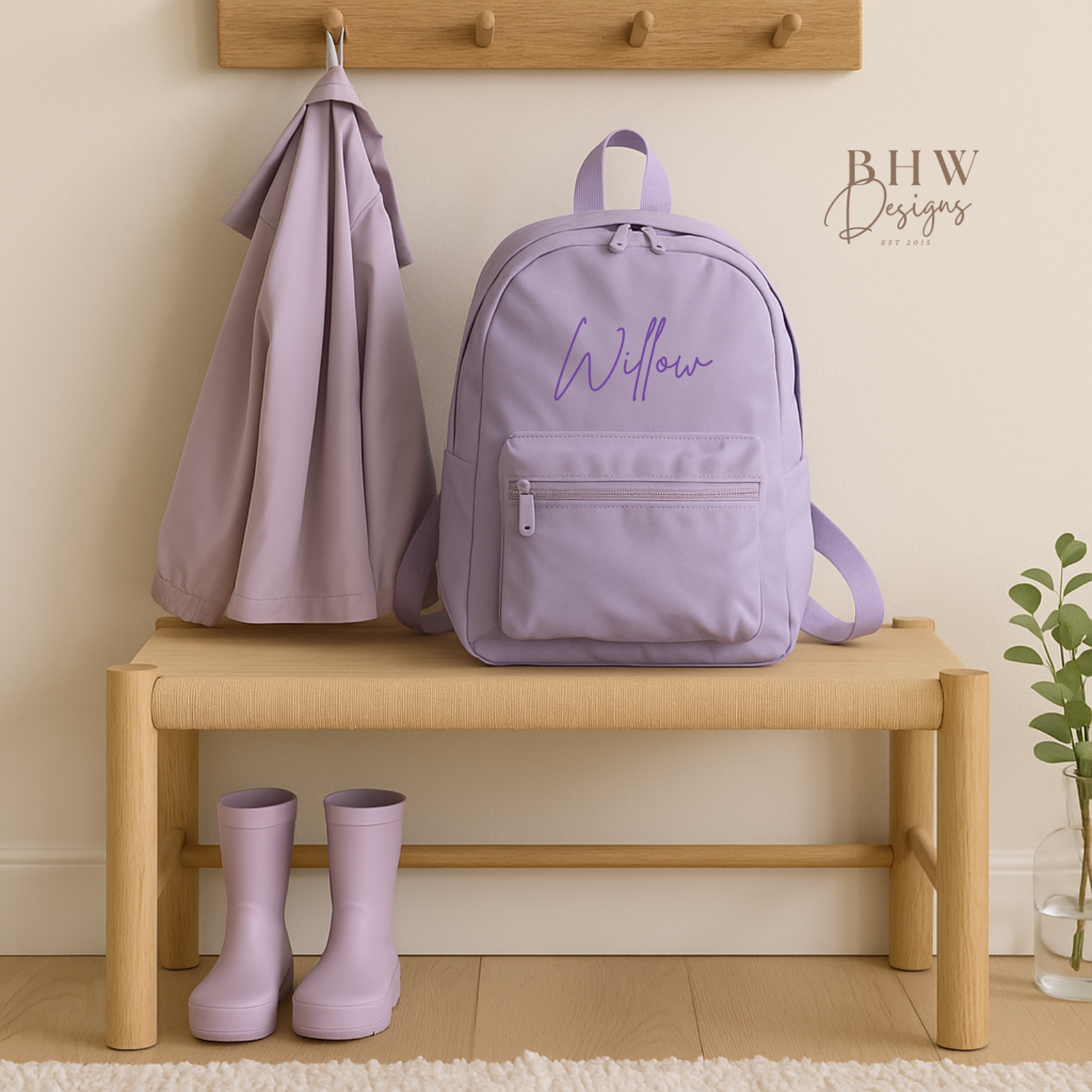 Lavender backpack with 'Willow' on a wooden bench with matching boots, against a neutral wall.
