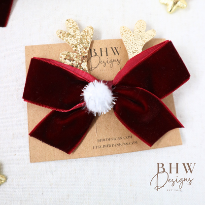 Red velvet bow with a white pom-pom on a brown card 