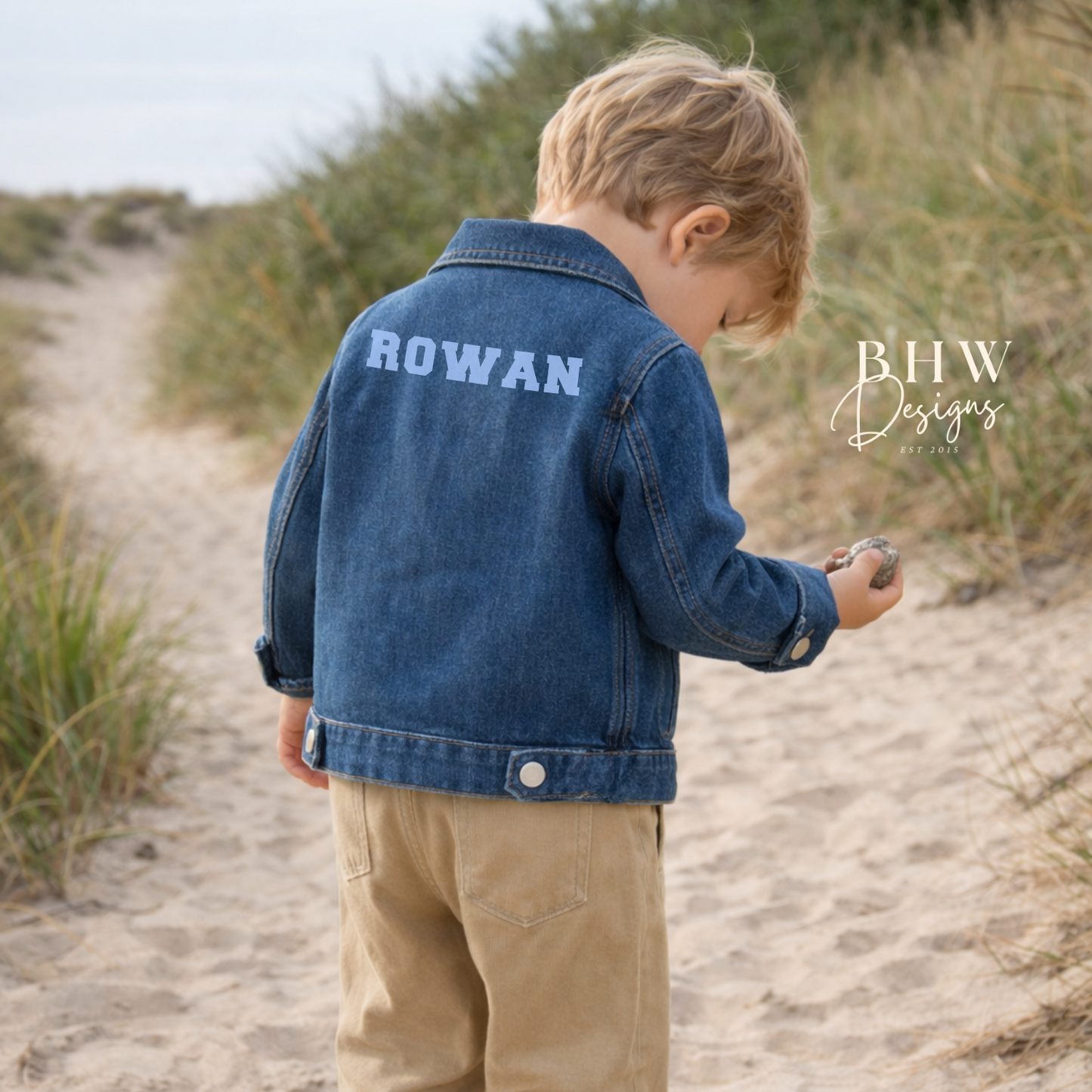 Child wearing a blue denim jacket with 'ROWAN' on the back in baby blue 