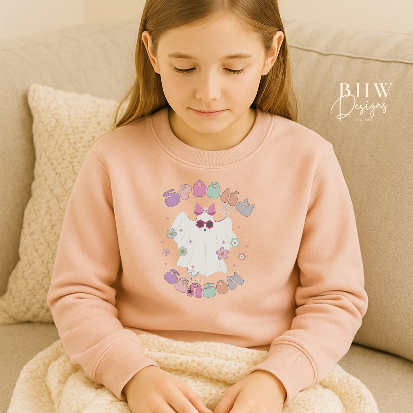 Young Girl wearing a pink sweatshirt with spooky season ghost design on the front 