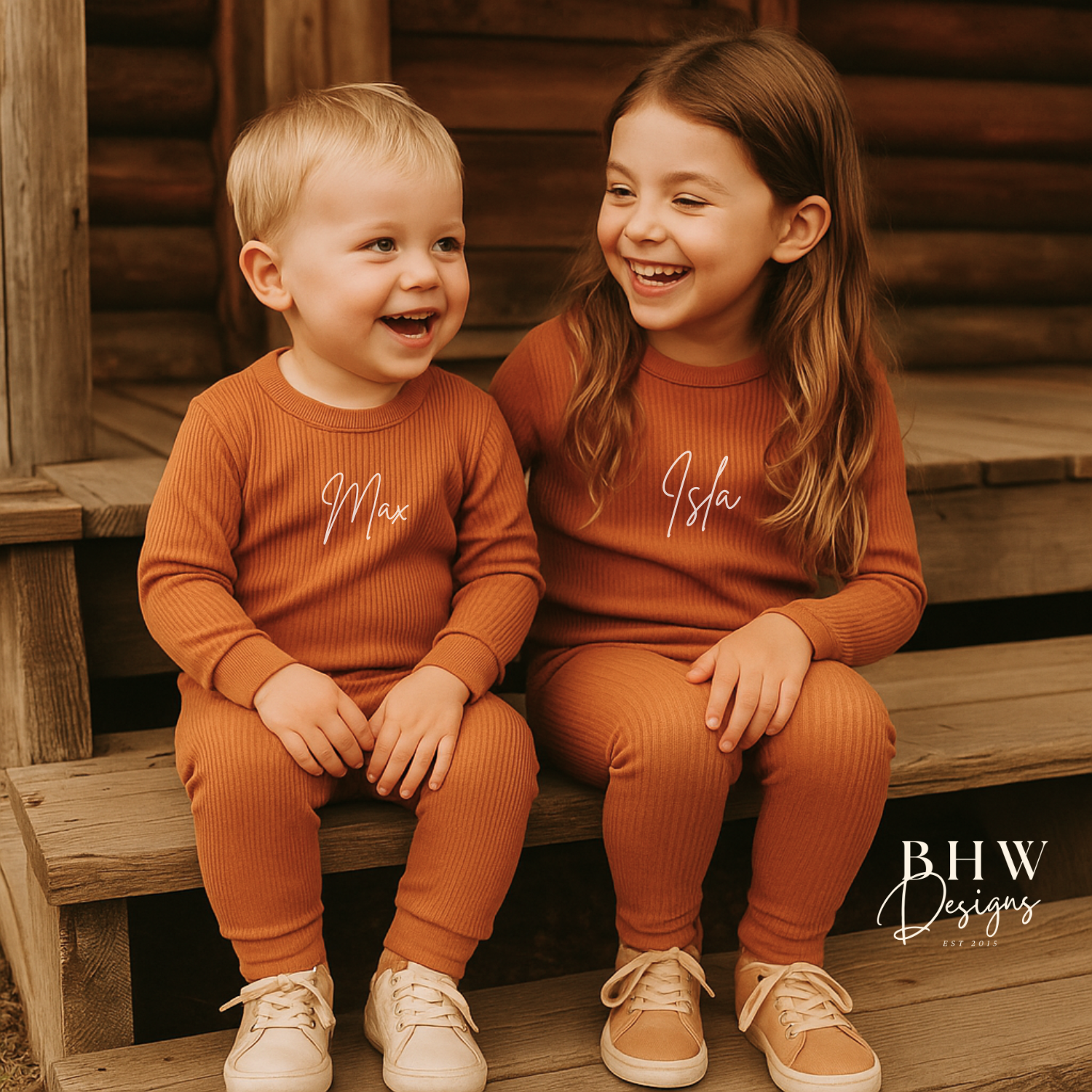 Two children in matching personalised ribbed rust outfits sitting on wooden steps,