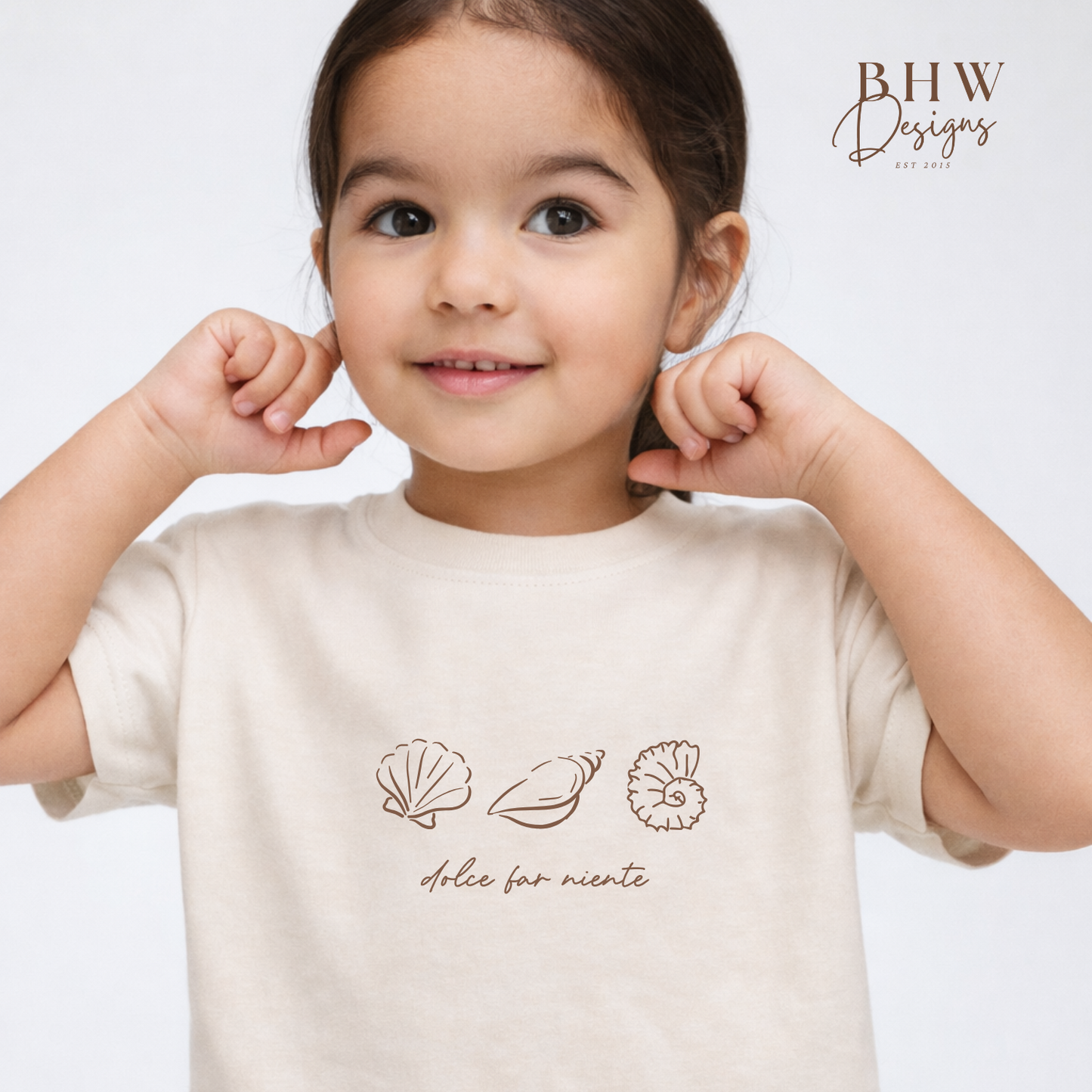 Child wearing a beige t-shirt with shell designs and text on a light gray background