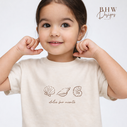 Child wearing a beige t-shirt with shell designs and text on a light gray background