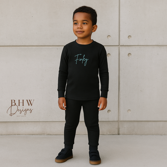 Child wearing a black ribbed long-sleeve shirt with 'Finley' printed on it. 