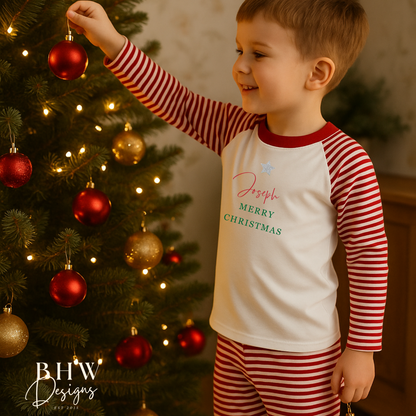 Child in personalised red and white striped pyjamas decorating a Christmas tree.