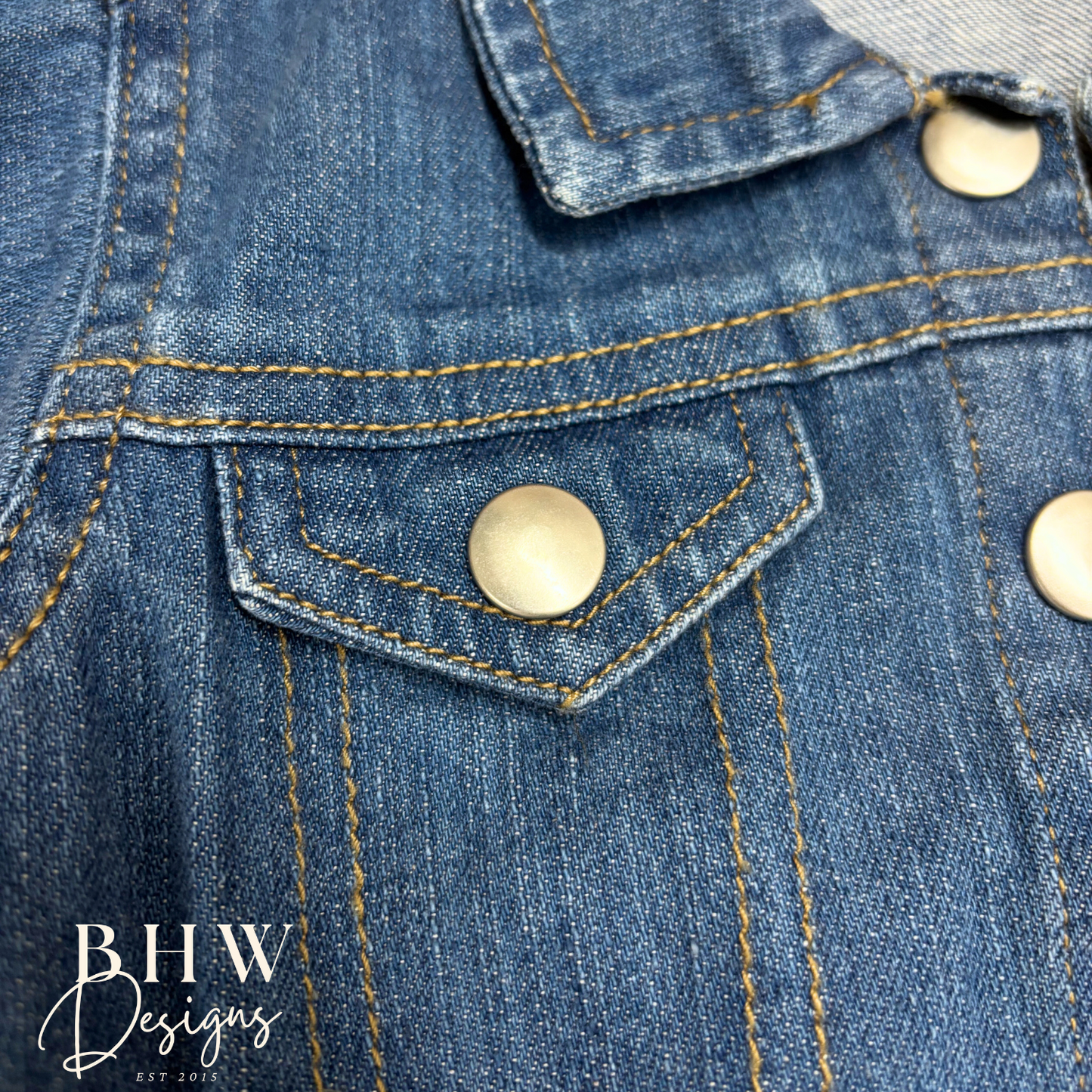 Close-up of a blue denim jacket with visible branding on buttons and collar.
