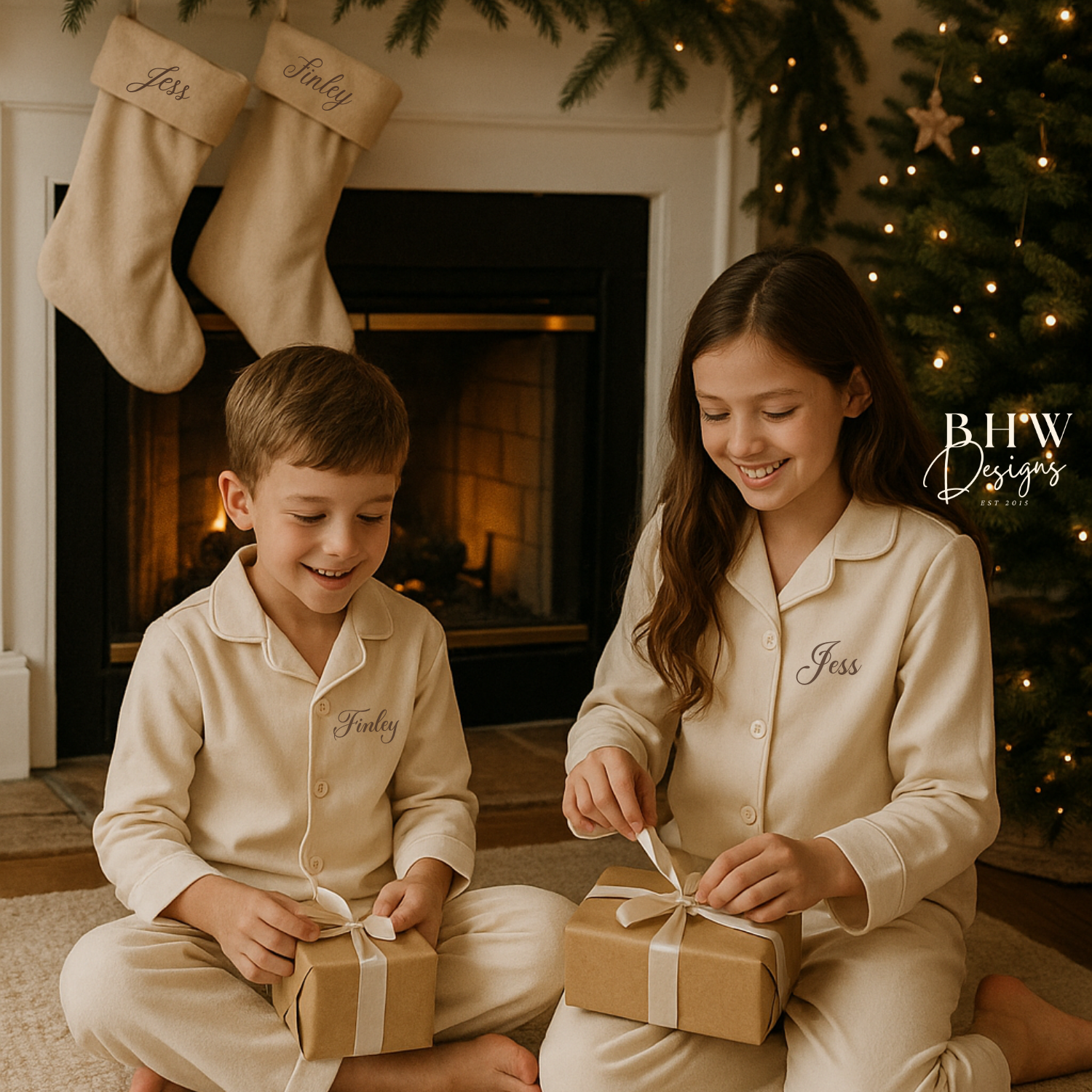 Two children in matching personalised beige pyjamas opening Christmas presents in front of a fireplace with personalised beige stockings hanging on the fireplace