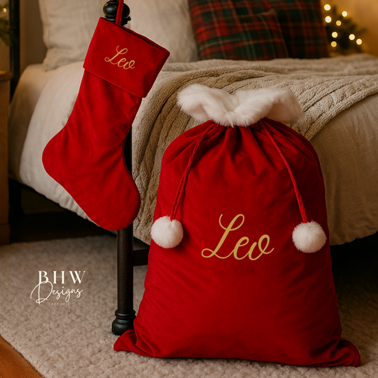 Red Christmas stocking and sack with 'Leo' on them, placed on a bed with festive decorations.