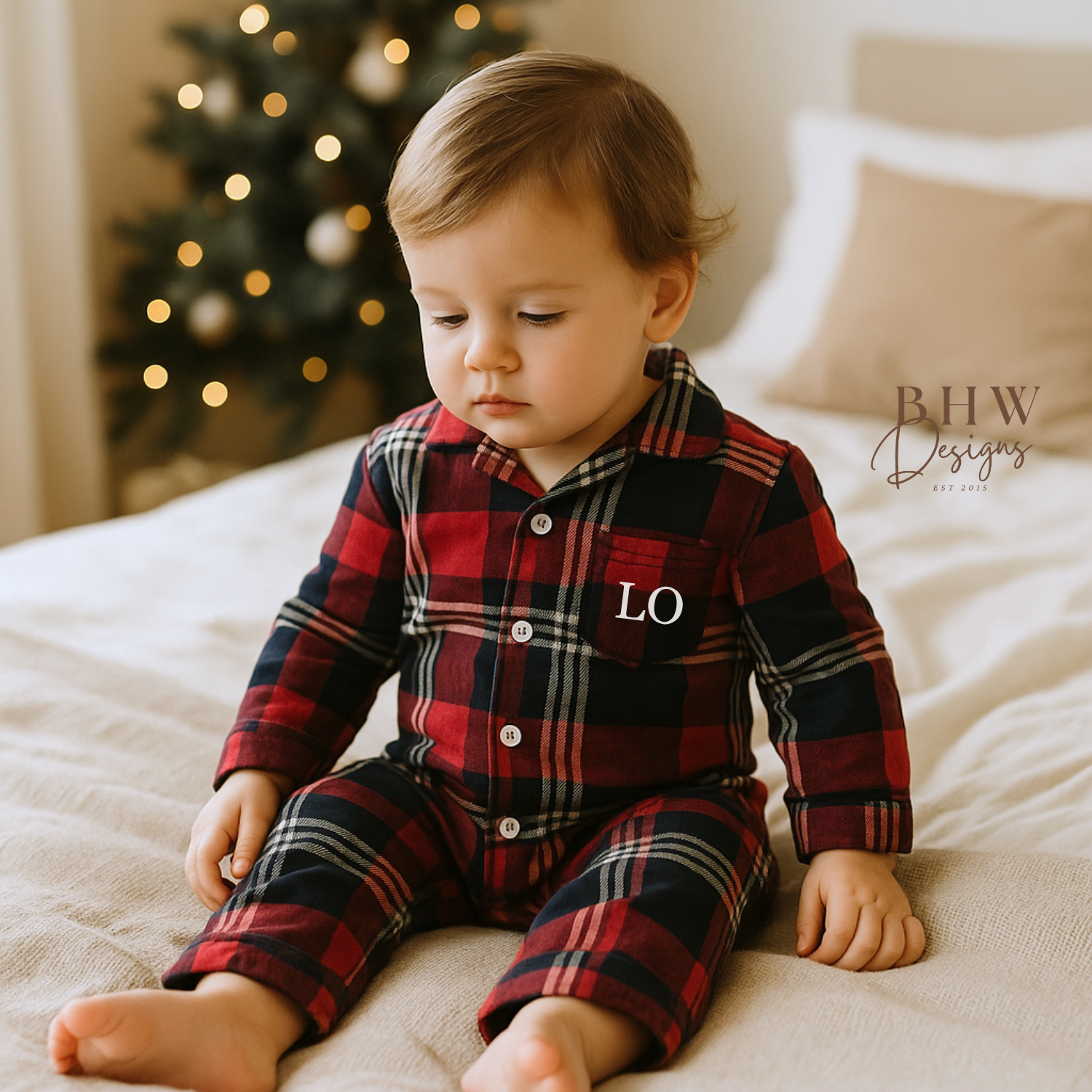 Baby wearing a red and blue plaid onesie with 'LO' on the frontb