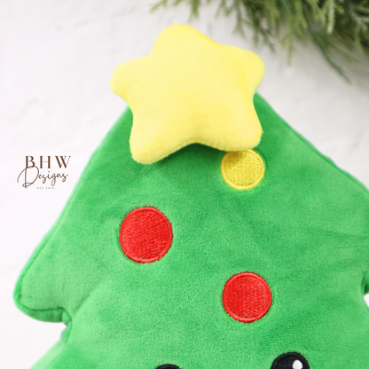 Green plush toy shaped like a Christmas tree with a star on top, red and yellow dots, and a smiley face.