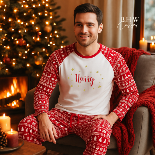 Man wearing red and white Christmas fair isle pyjamas with 'Harry ' printed on them in red adorned by gold stars, sitting in a cozy room with a Christmas tree and fireplace.