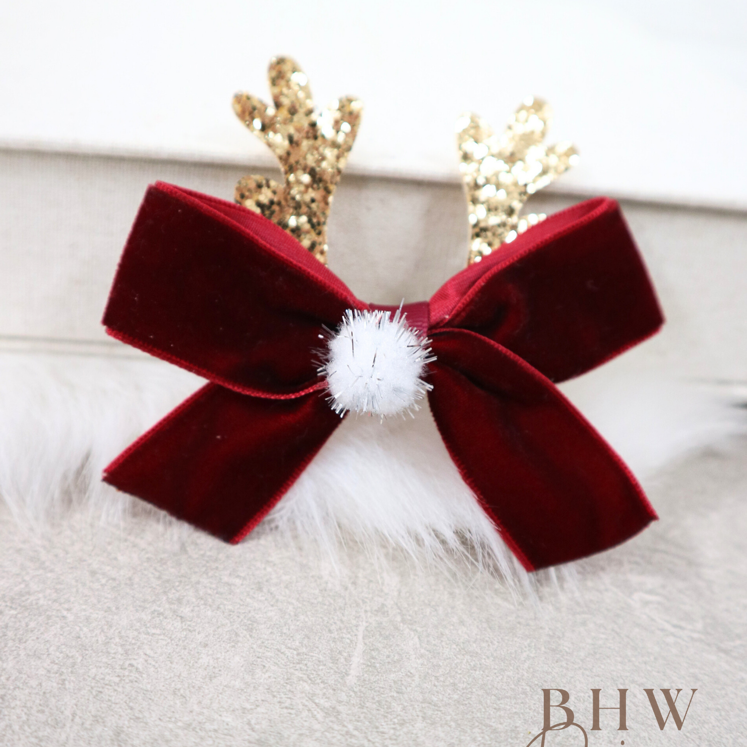 Red velvet bow with a white pom-pom and gold antlers 