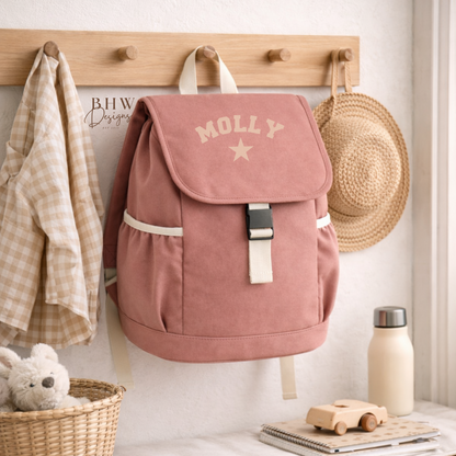 Pink backpack with 'MOLLY' branding hanging on a wooden wall hook with a bench and toys in the foreground.