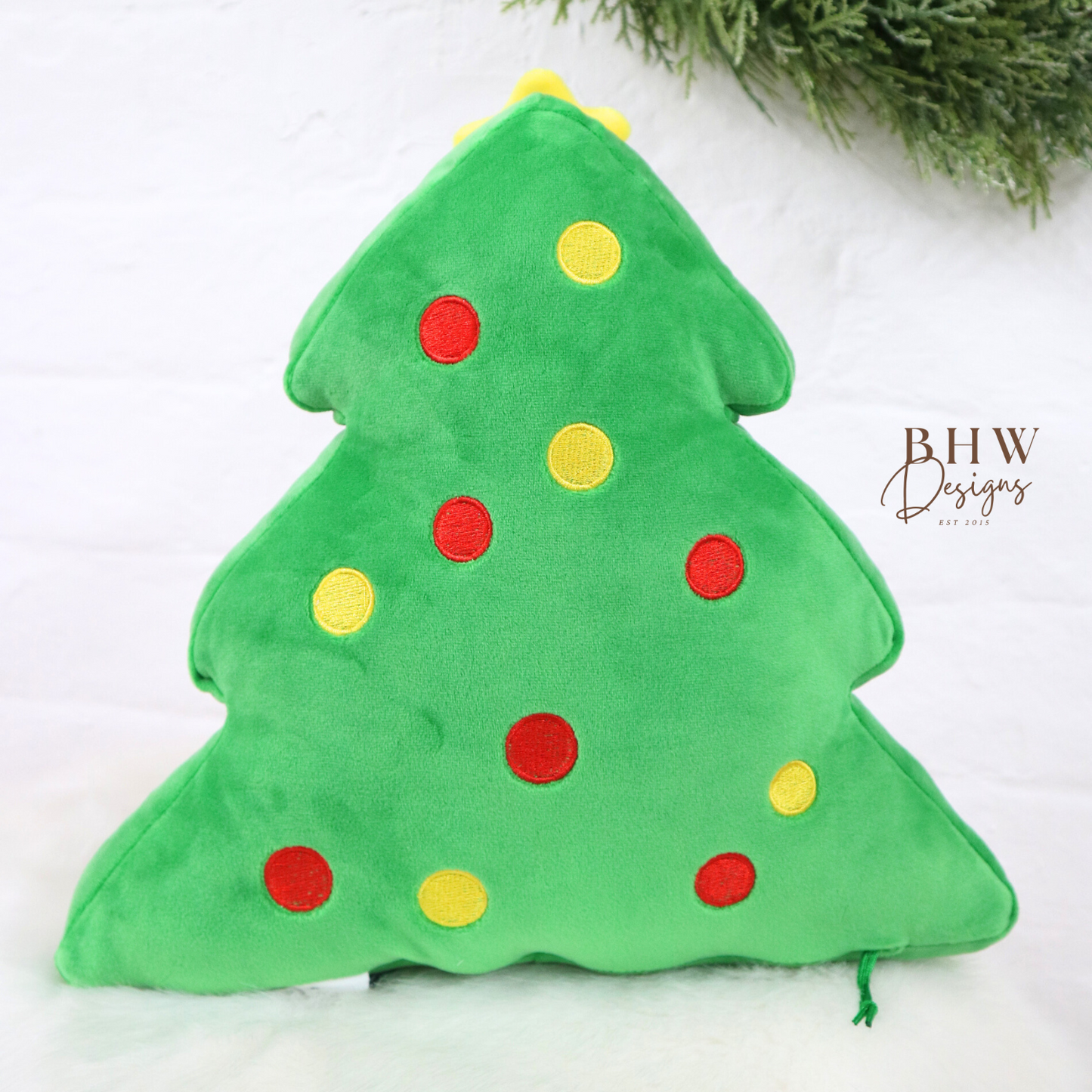 Green Christmas tree-shaped pillow with red and yellow dots on a white background