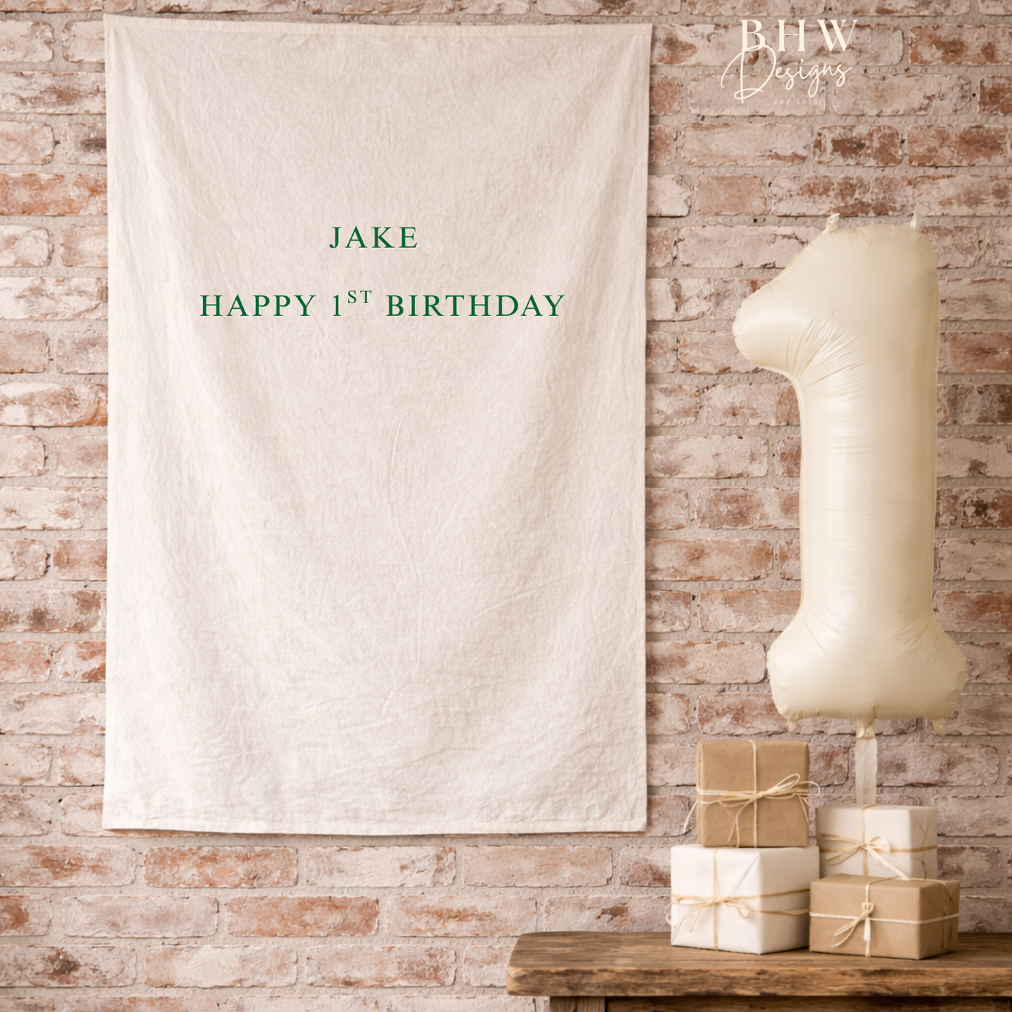 Personalized birthday banner with 'JAKE HAPPY 1ST BIRTHDAY' text on a brick wall background.