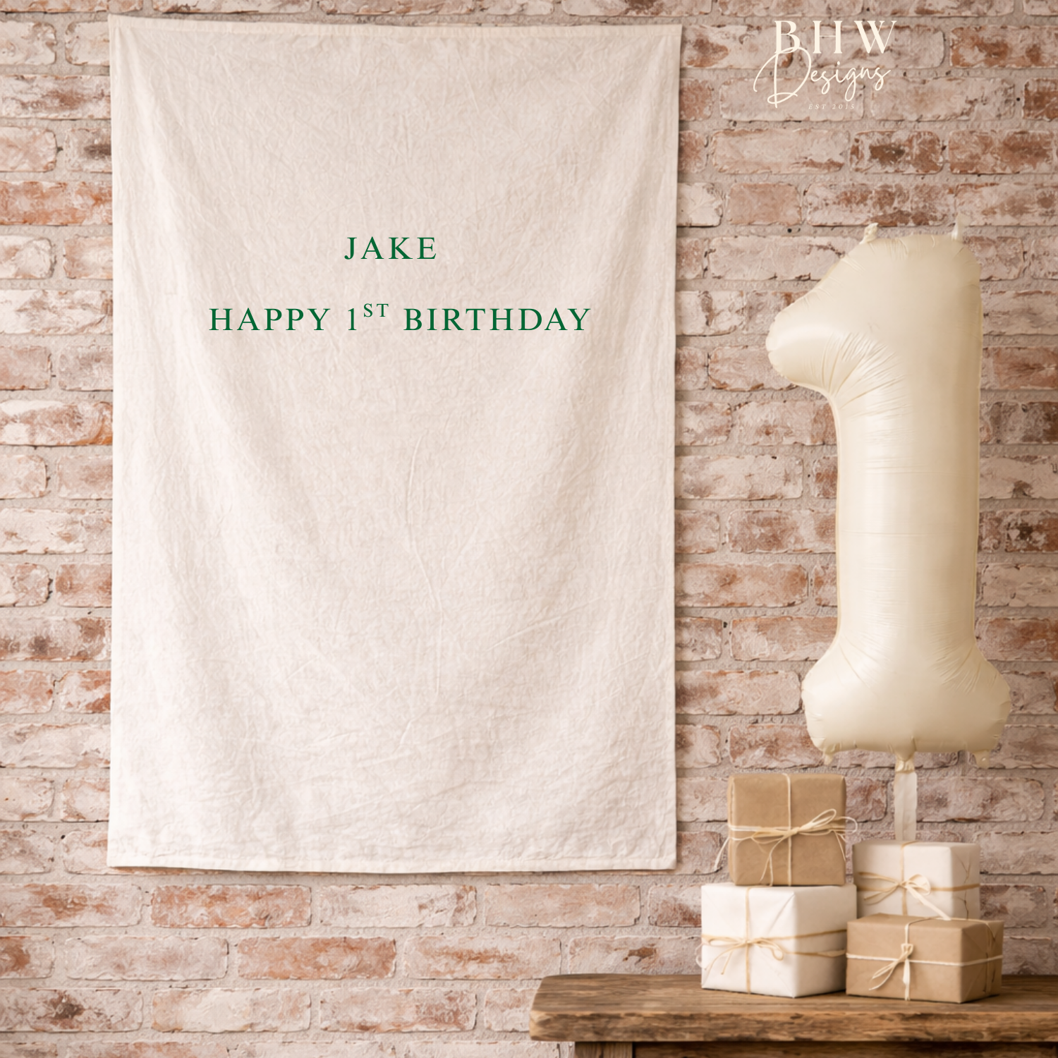 Personalized birthday banner with 'JAKE HAPPY 1ST BIRTHDAY' text on a brick wall background.
